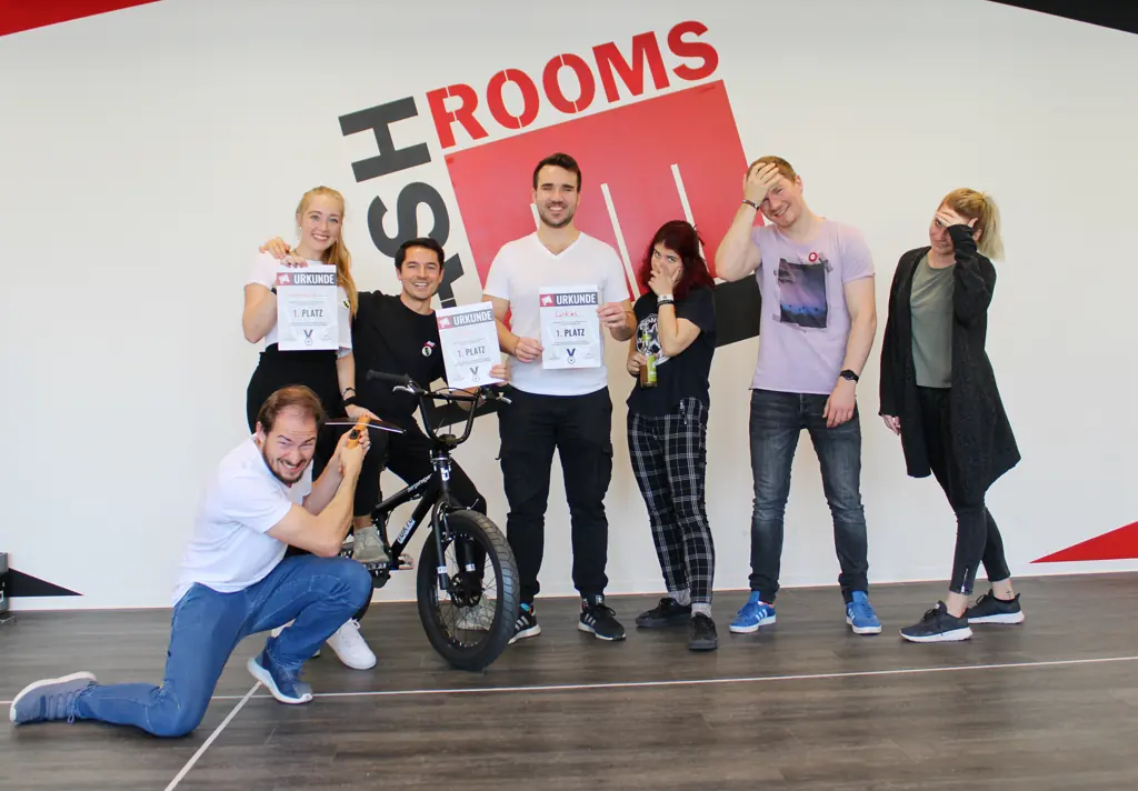 Sechs Freunde mit Urkunden, einer kniet vor einem BMX-Rad und tut so, als repariere er es